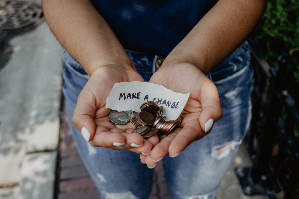 a pair of hands put together, filled with coins and a piece of paper that says "make change"